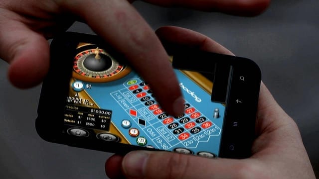 Man playing roulette on his smartphone; image by BagoGames, via Flickr, CC By 2.0, no changes.