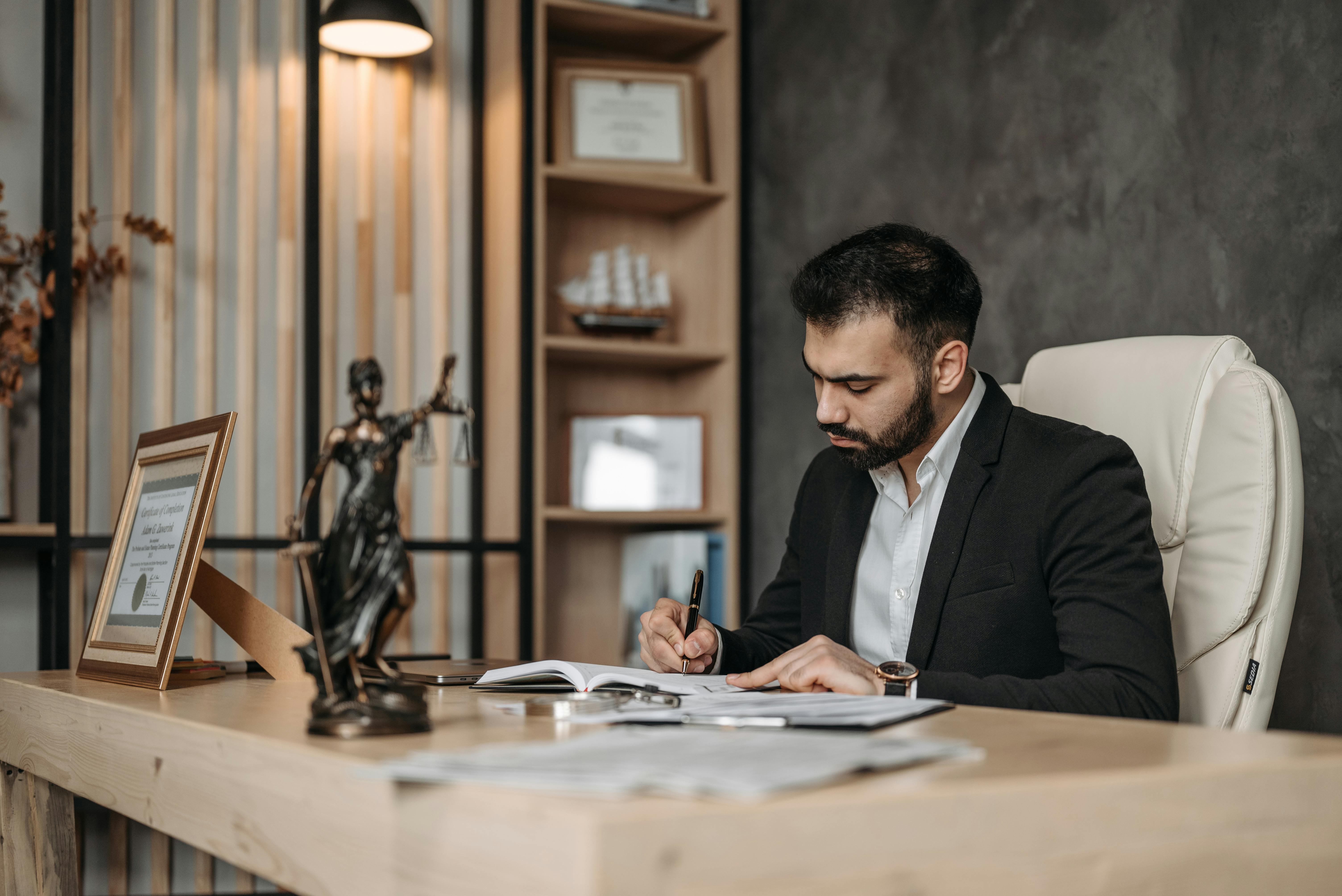 Lawyer at desk writing in notebook; image by Pavel Danilyuk, via Pexels.com.